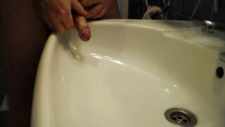 John is Peeing into the Bathroom Sink